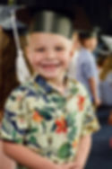 A Lakeside Charter Academy male kindergartener at kindergarten graduation looks at the camera and smiles broadly.