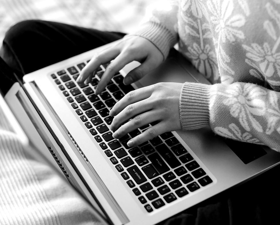 Black and white image of young hands typing on a laptop