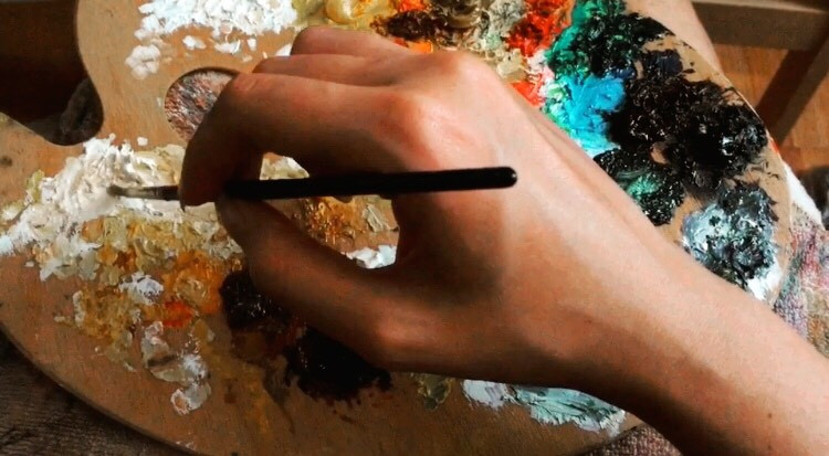 Hand holding a paint brush, palette, oil paints, mixture of paint, mediums