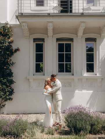 Hochzeitspaar küsst sich vor weißem Haus