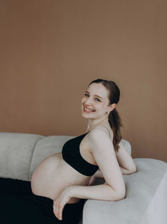Lächelnde schwangere Frau auf Sofa im Fotostudio Aalen Vollformat