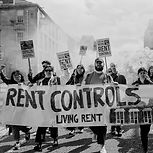 People at a protest holding a banner that says 'Rent Control, Living Rent'. The photo is in black and white 