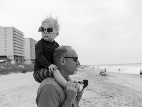 Un père ou grand-père qui porte son fils/petit fils sur ses épaules à la plage 