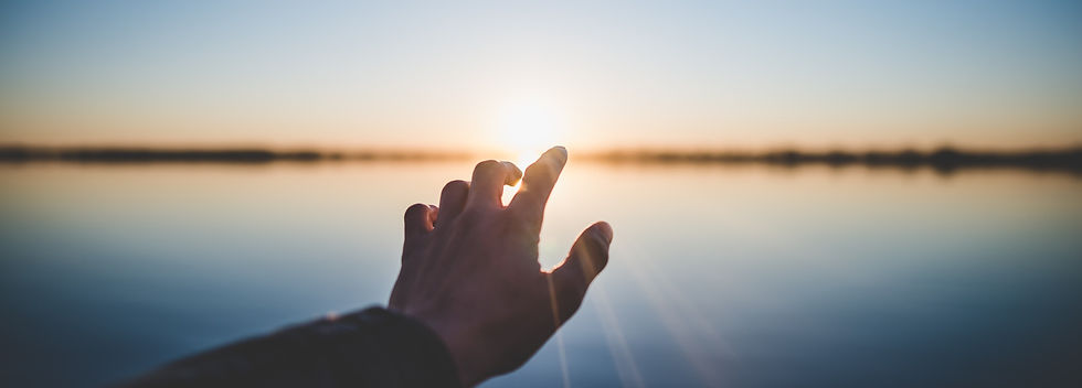 Hand reaching towards sunrise