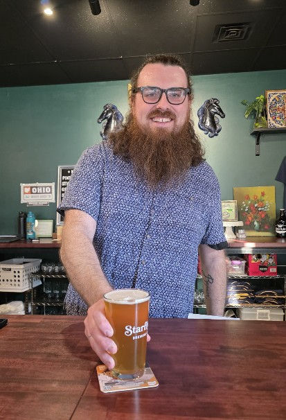 Owner Andrew Archer serving a craft beer across the bar at Starflyer Brewing Company.
