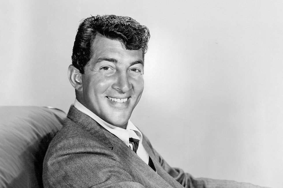 Black-and-white portrait of a young Dean Martin smiling while wearing a patterned suit and tie.