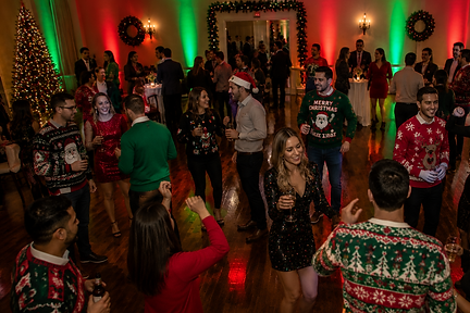 Guests dancing at a holiday party with festive decorations and uplighting