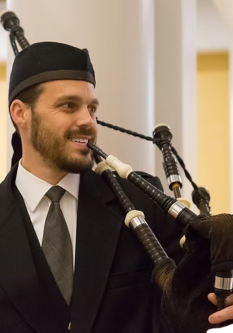 Highland Bagpiper Christian Hunter from Solon, OH smiling in a professional photo while holding his instrument