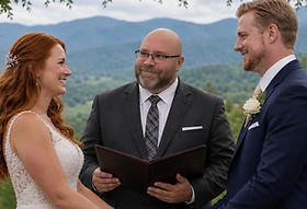 Wedding officiant leading ceremony as couple holds hands during vows at altar