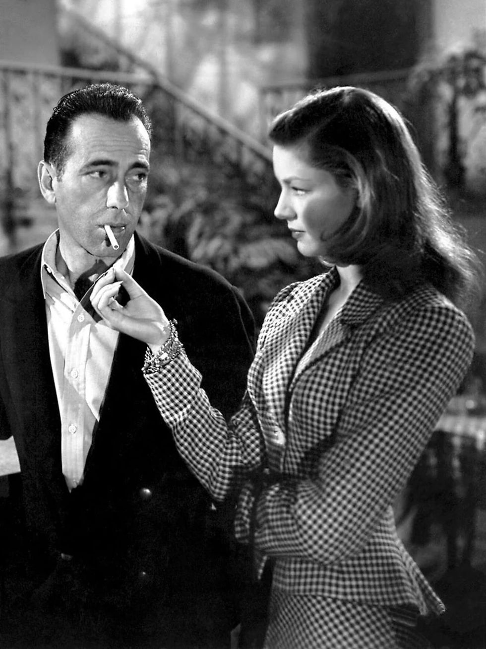 Black-and-white film still of Humphrey Bogart lighting a cigarette as Lauren Bacall looks at him during a scene from To Have and Have Not.