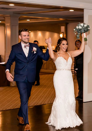 Newly married couple making their grand entrance into their wedding reception as guests cheer and celebrate.