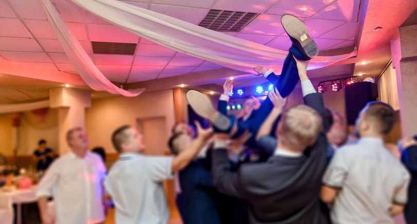 Groomsmen lifting the groom above the dance floor during a wedding reception.