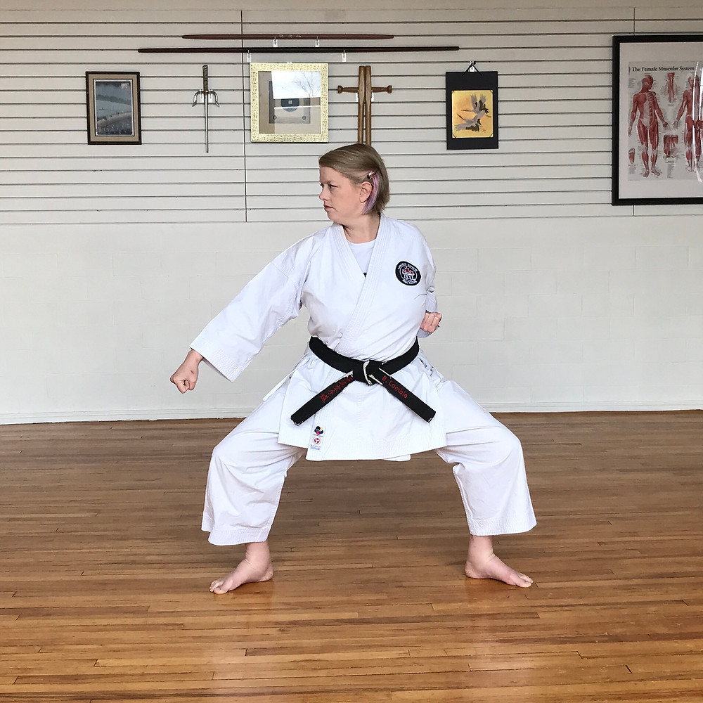 Sensei Barb performing a low block in shake dachi. Ankles are visibly swollen.