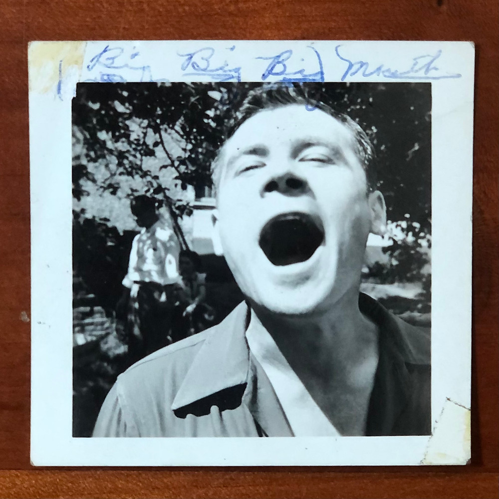 Black and white photograph of a man laughing with his mouth open wide.