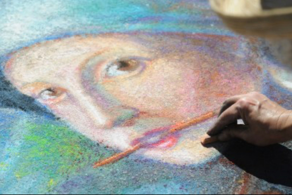 Close-up of a portrait of a woman painted on a sidewalk in pastel.