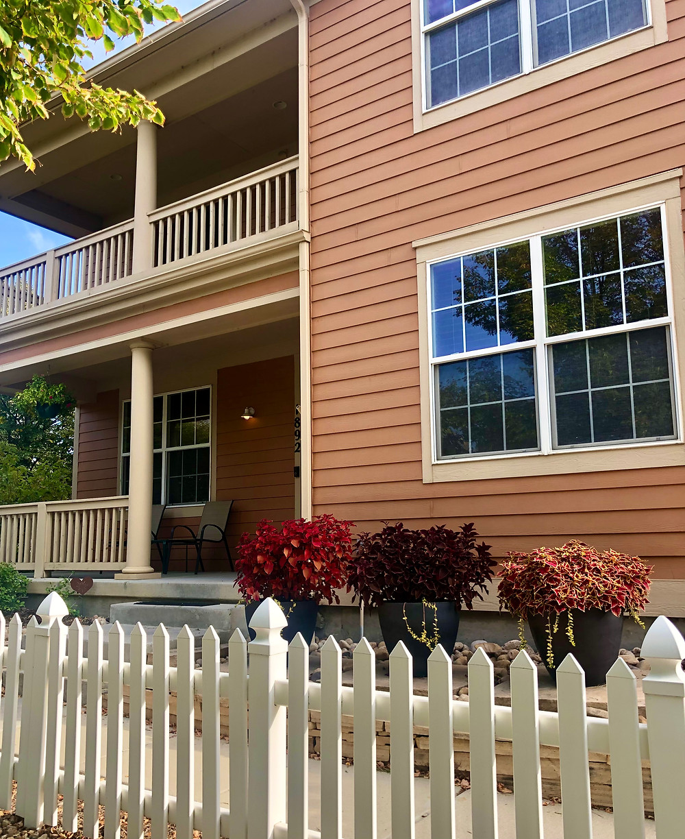Front of a two-story house with pots of coleus in front.