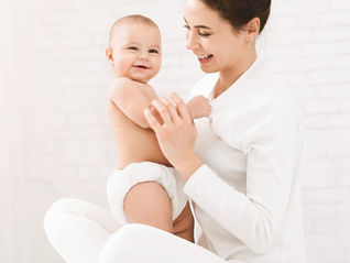 Mother holding baby six weeks postpartum in soft neutral setting