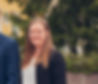En leende Anna Andersson utomhus med Bissaccs kontor och ett träd i bakgrunden.
