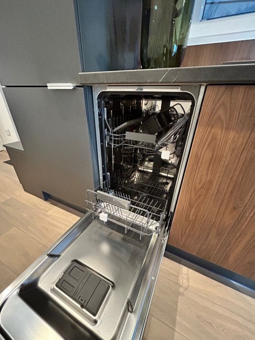 Miniaturbild: Máquina de lavar loiça aberta, mostrando pratos e utensílios em seu interior.