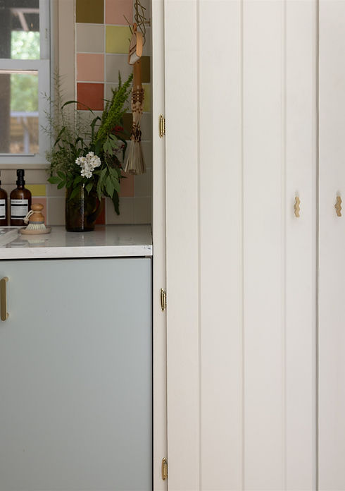 Vase of flowers on kitchen counter, blue cabinet, and pantry doors.