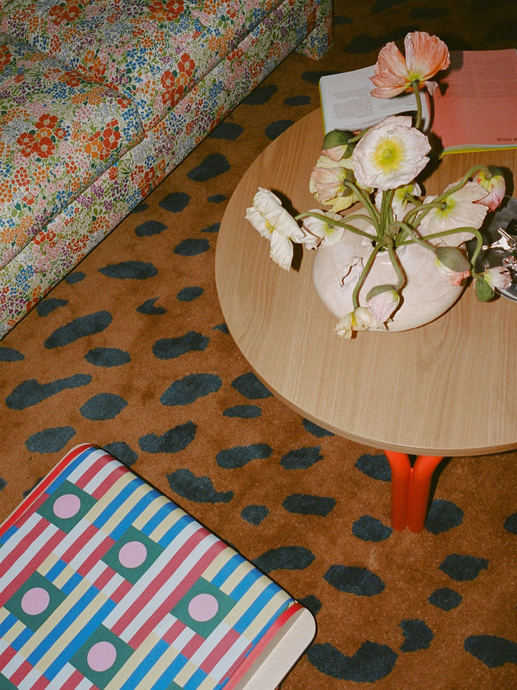 Round coffee table with flowers, patterned rug, floral sofa