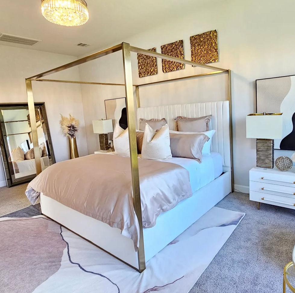 A stylish bedroom featuring a gold-framed canopy bed, neutral bedding, abstract wall art, and a crystal chandelier for a refined, contemporary look.