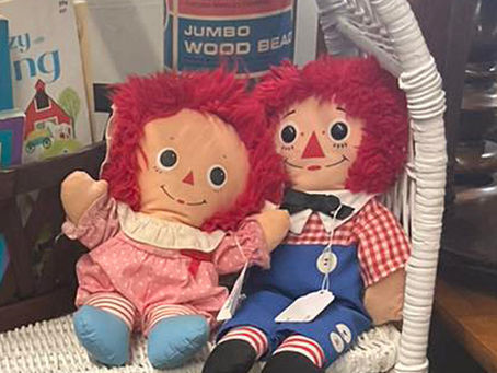 Vintage Raggedy Ann and Andy dolls on wicker shelf