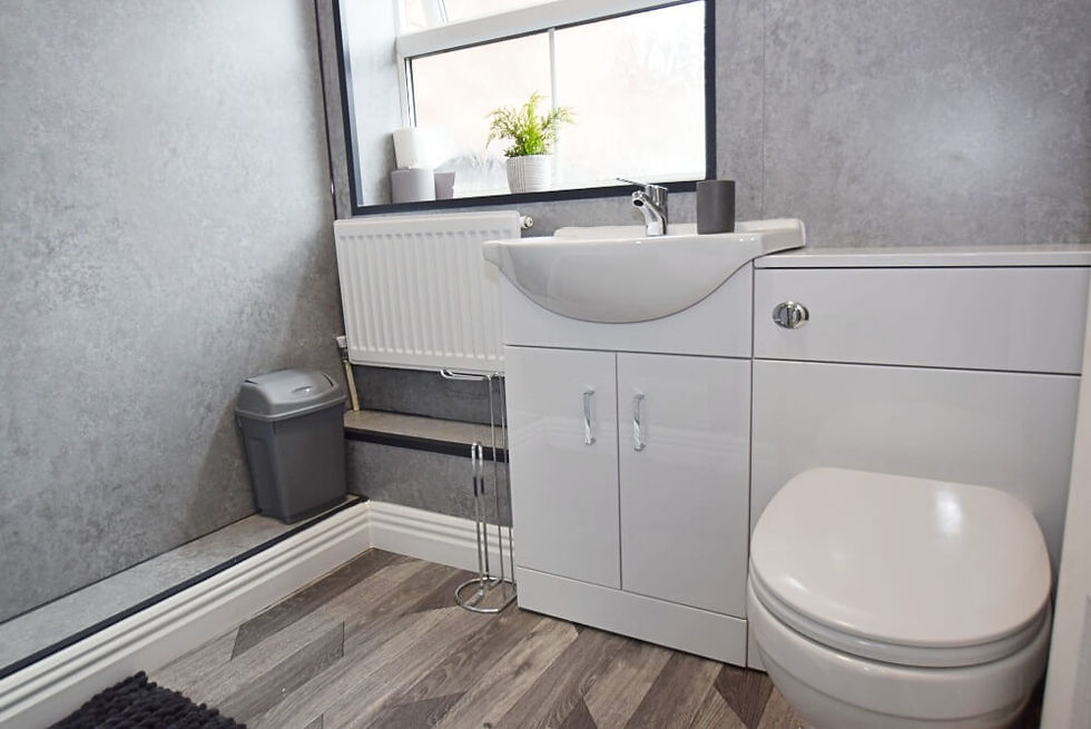 Bright bathroom with grey walls and white bathroom units (toilet and sink).