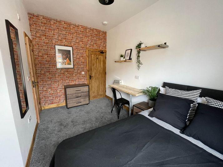 Large double bedroom furnished to an extremely stylish and high standard, with a large double bed and wooden drawers, as well as a desk area for studying. 