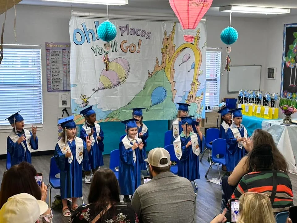 Kinder-Prep graduates standing together in blue caps and gowns during their graduation ceremony