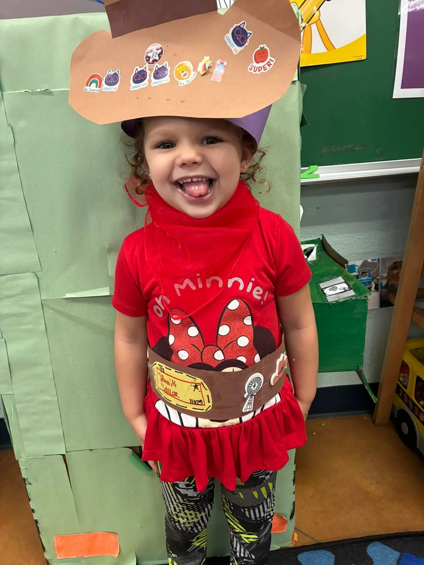 A smiling child wearing a handmade cowboy hat and red bandana at school
