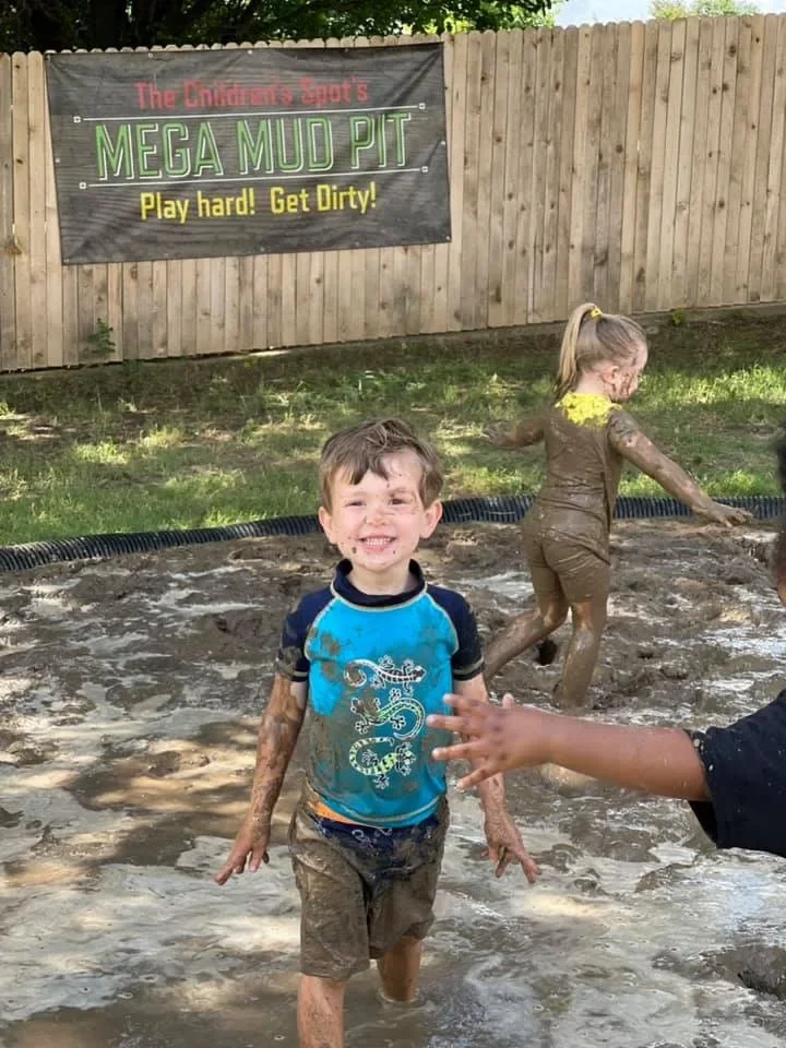 A smiling child covered in mud in The Children’s Spot Mega Mud Pit