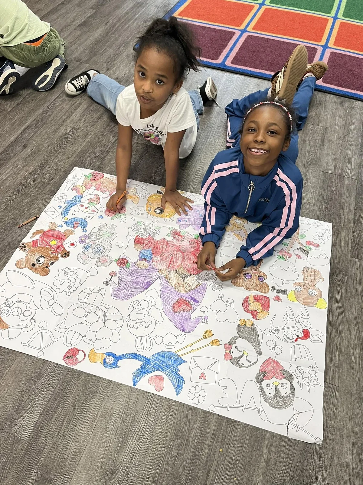 Two children sharing a large colorful drawing in their classroom in February 2026