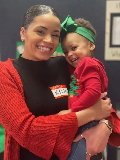 A smiling adult holding a laughing young child at The Children’s Spot