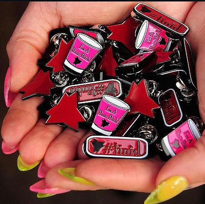 Hands holding a cluster of the enamel pin options 