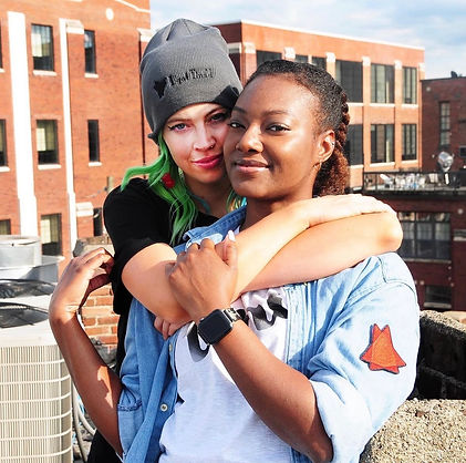Close up of the two female models highlighting the "I got tini'd" beanie hat and the - tini - logo clothing patch