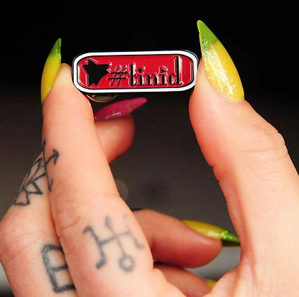 Close up of the "#tini'd" enamel pin
