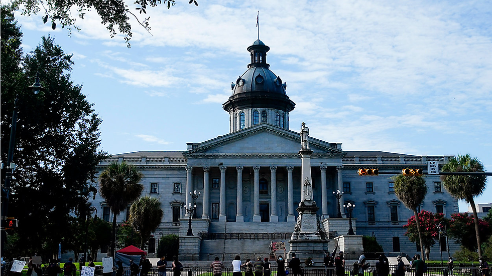 People stand in front of the South Carolina State House Friday, July 10, 2020, in Columbia, S.C. (AP Photo/Chris Carlson)