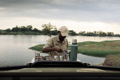 A local guide pouring coffee at the morning game drive coffee stop next to the mighty Zambezi river