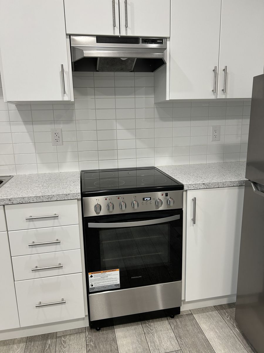 A spotless stove and white kitchen after a regular clean