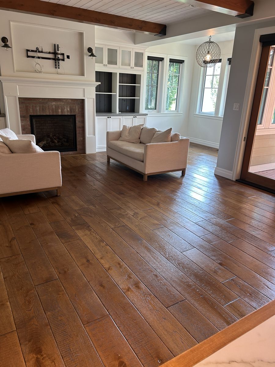 A living room with a fireplace and gleaming wood floors after a K.Cleaners clean