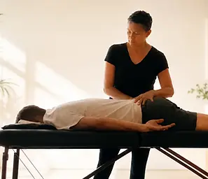 Practitioner performing Spinal Flow Technique on a client lying on a treatment table.