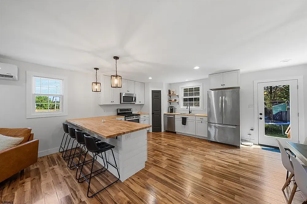 Open concept kitchen with large island peninsula, butcher block countertops, and white cabinets