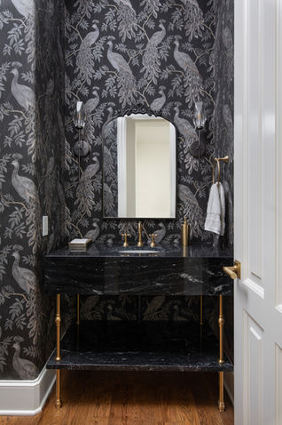 Ornate wall wallpaper, Bold bird pattern, Black marble vanity, Polished stone top, Brass vanity legs, Sturdy metal supports, Gold faucet fixtures, Elegant metallic spout, Framed wall mirror, Arched black frame, Sconce wall lights, Decorative metal lamps, Wall-mounted towel ring, Brass circular holder, Glossy stone shelf, Coordinating marble slab, Hardwood floor finish, Warm oak planks, Textured wall accents, Raised wallpaper design, Polished brass hardware, Gleaming door handle, Matching soap dispenser, Coordinated gold design, Recessed sink basin, Smooth under-mount bowl, Painted door trim, Crisp white borders, Glossy cabinet finish, Reflective black surface, Subtle grout lines, Seamless wall detailing, Dark color palette, Sophisticated monochrome tones, Tall decorative wainscoting, Half-wall wooden panel, Minimalist towel placement, Neatly draped fabric, Narrow room layout, Space-efficient design.