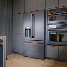 Gray cabinets, Flat panel cabinets, Bronze pulls, White oak, Square stone Backsplash gray marble wraparound island countertop, Gray panel appliances, White oak flooring, Natural light, 