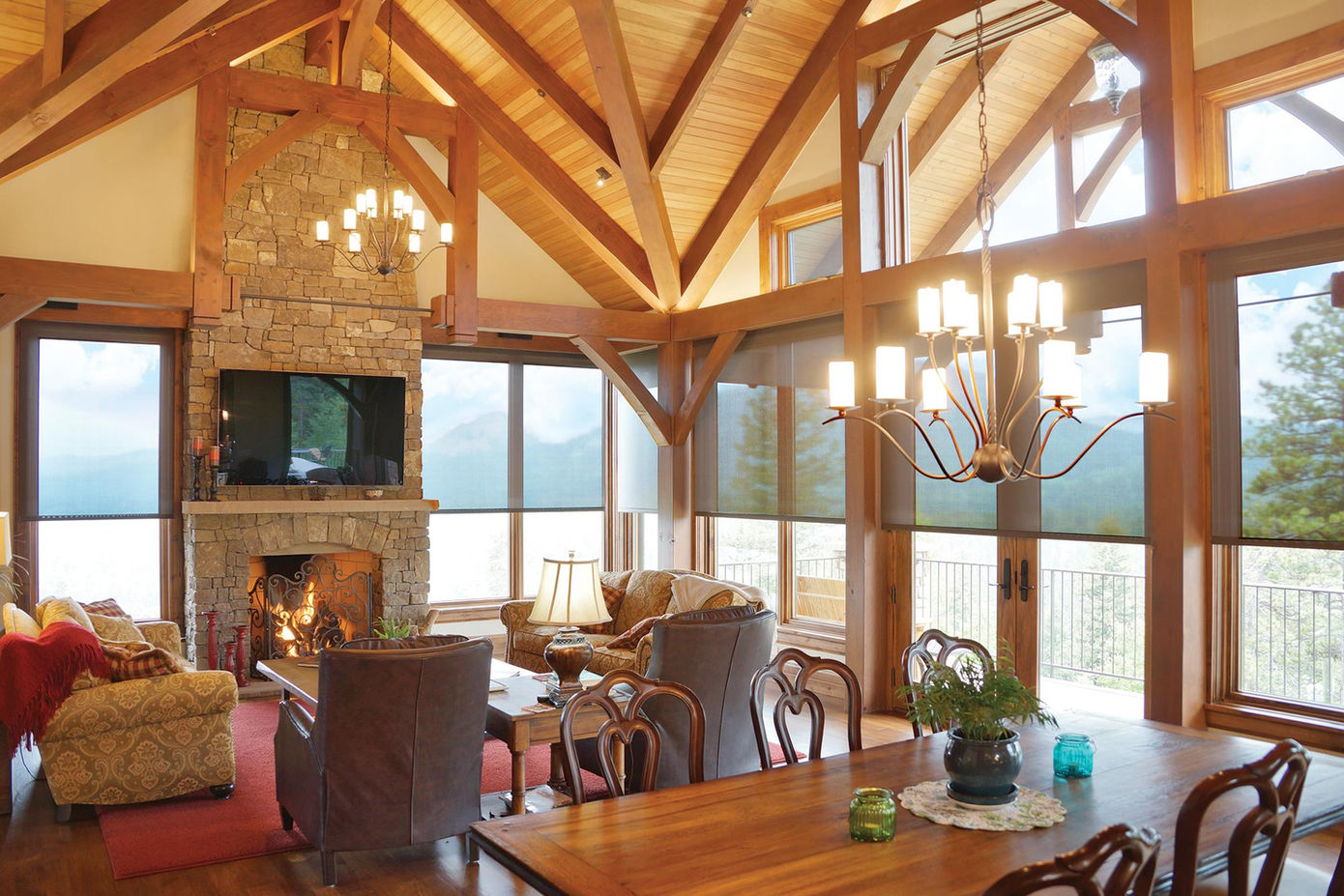 lodge style home with exposed wood beams, large windows, a stone fireplace and roller shades