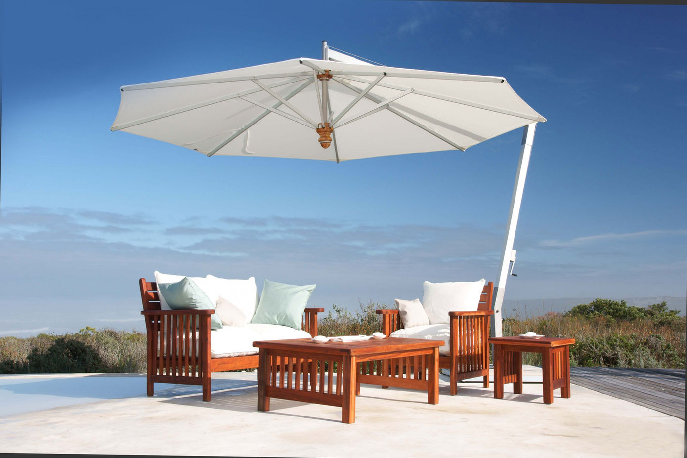 stand umbrella covering a wood chair and wood couch with pillows