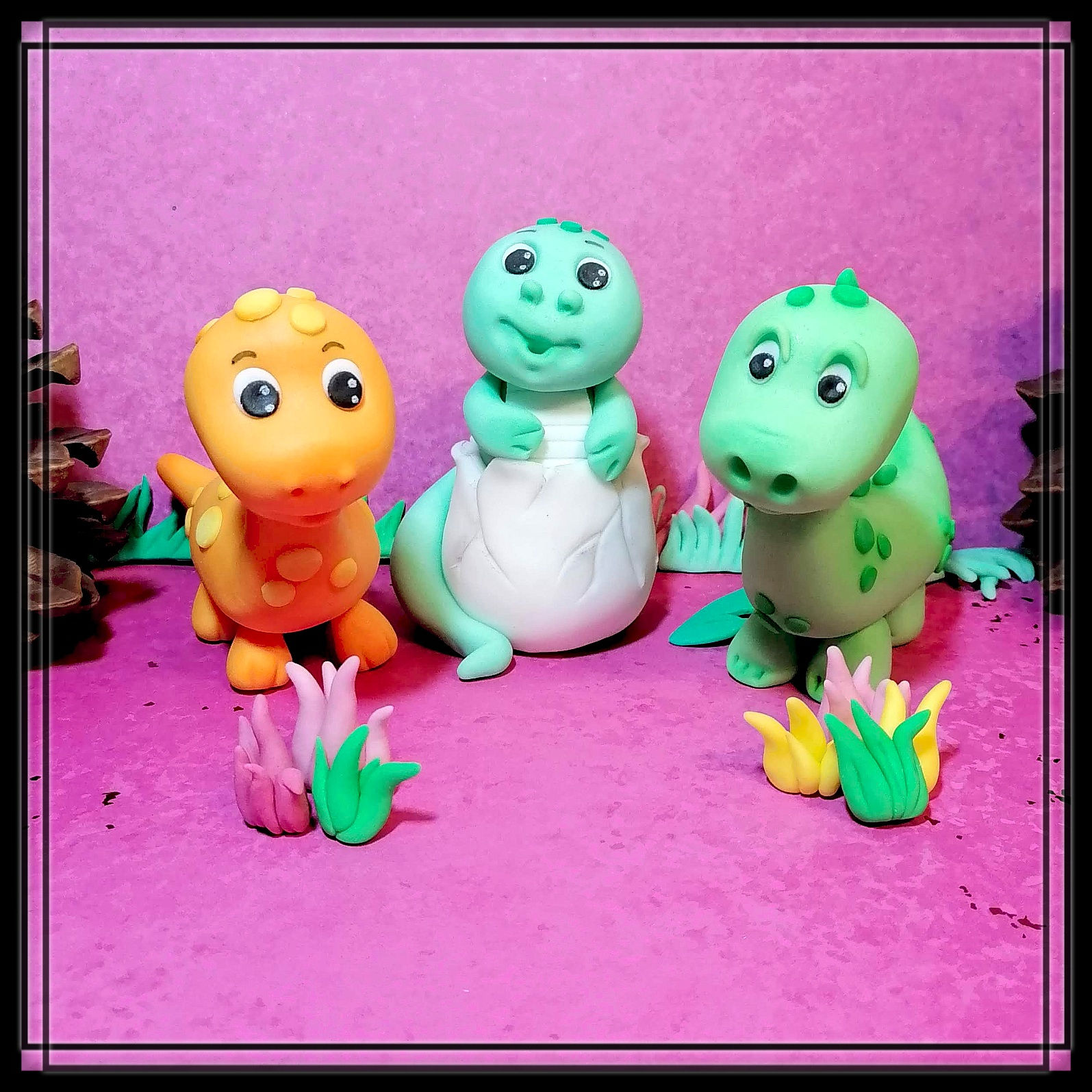 Drei bunte Fondant Dinosaurier als Tortenfiguren - ein grüner Dino schlüpft aus einem Ei, orangefarbener und grüner Dino