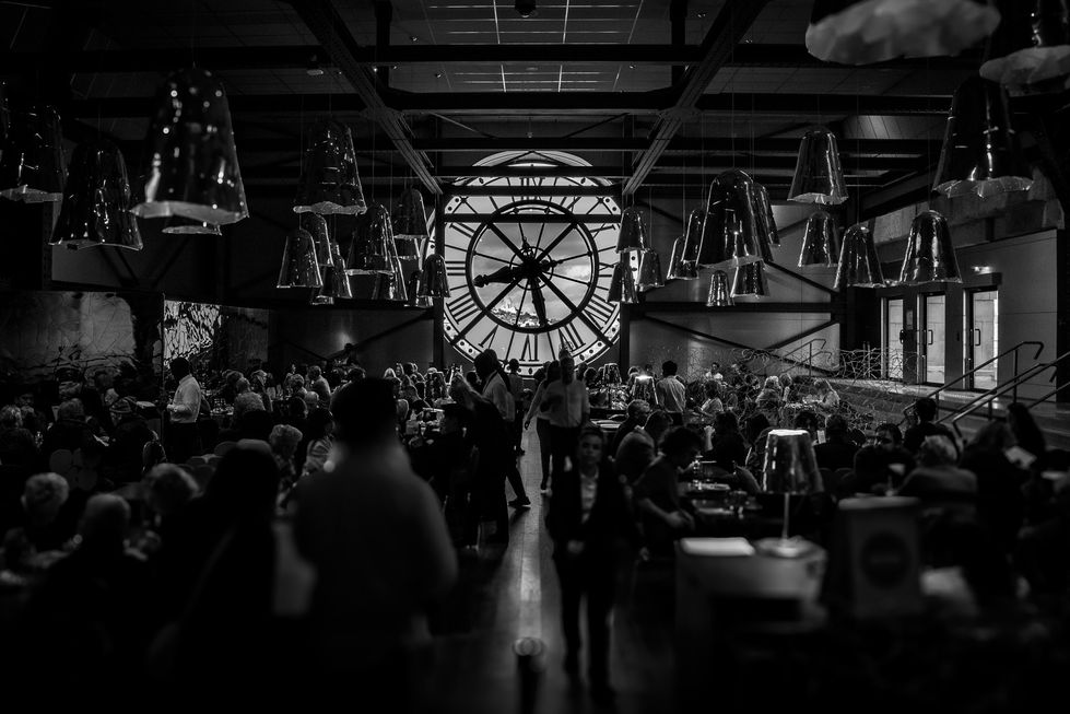 black and white picture of busy restaurant with a clock on the background