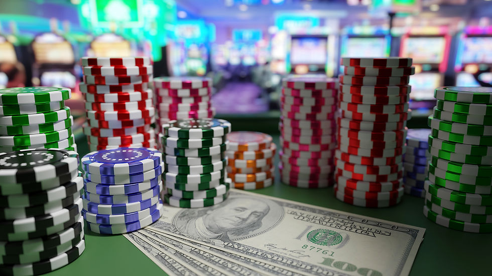 Stacks of colorful poker chips on a casino table with hundred-dollar bills. Blurred slot machines in the vibrant background.